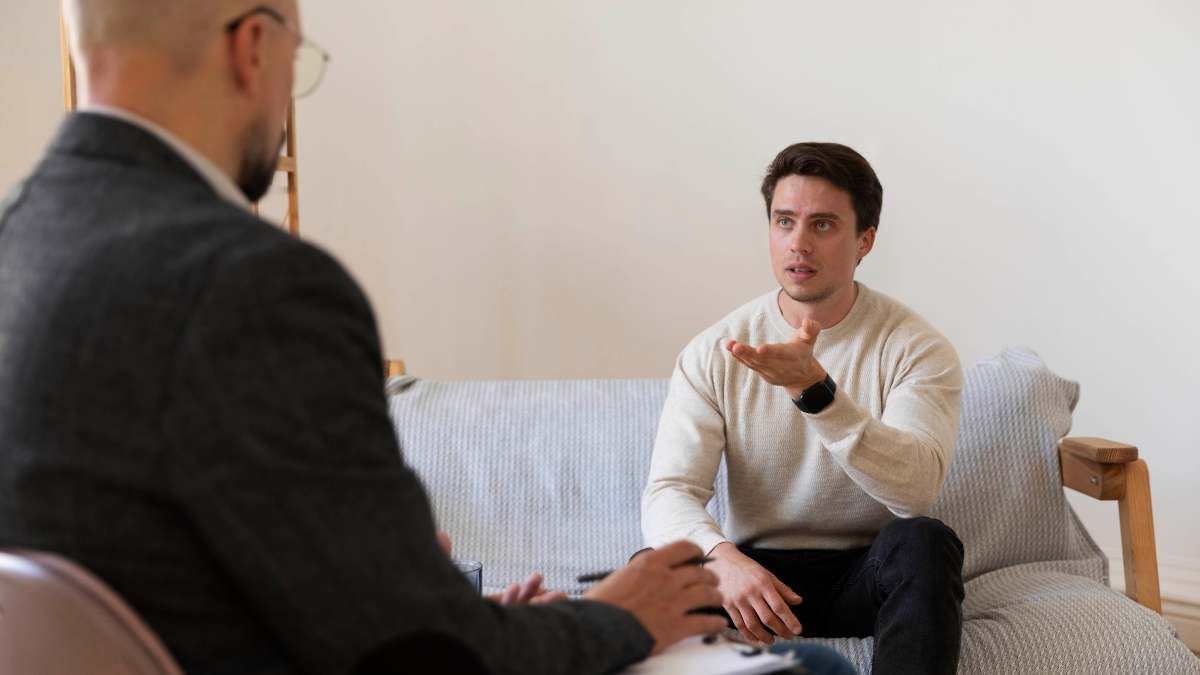 Male patient addressing personal challenges in therapy session, questioning "Do I need rehab?" with his therapist.