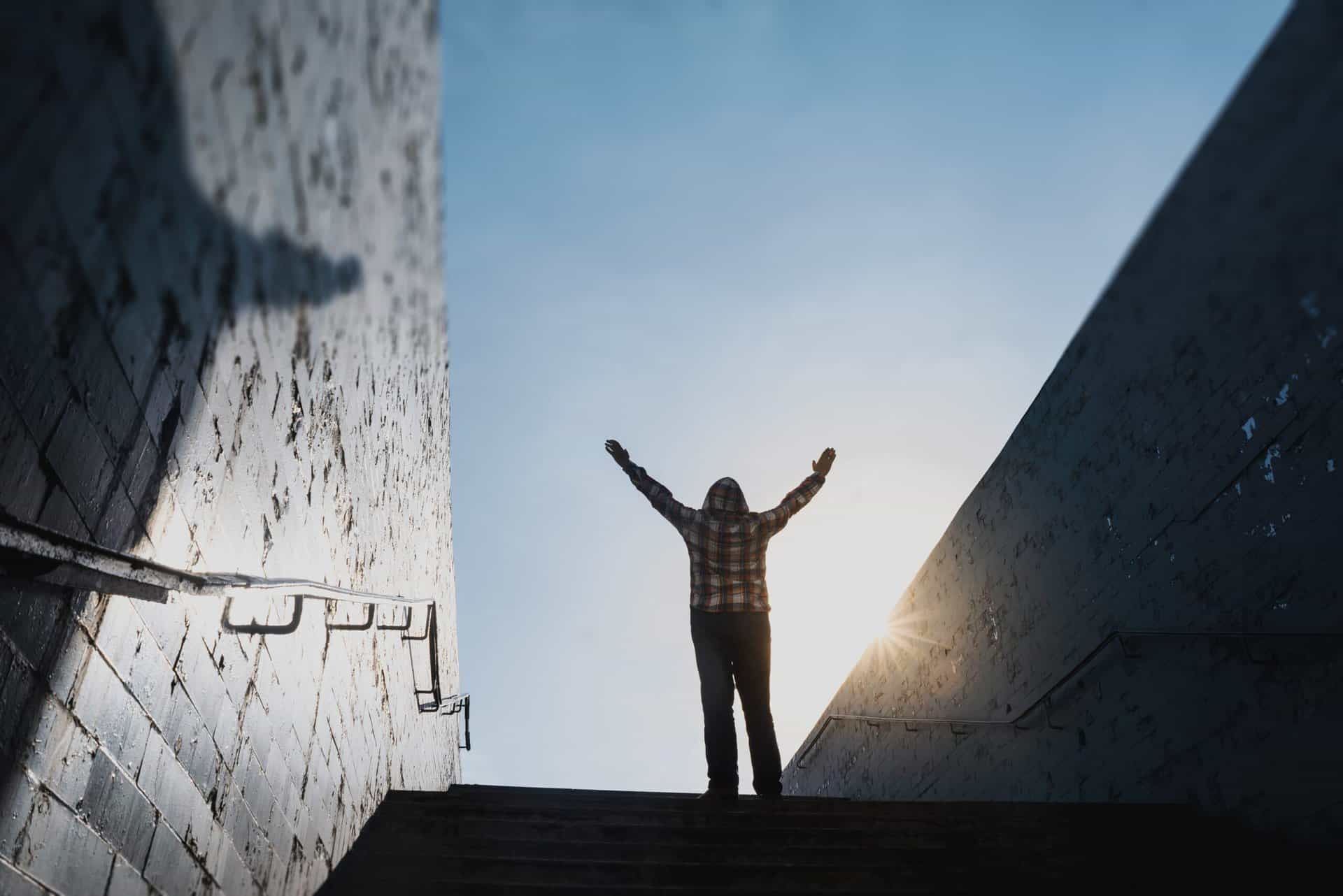 Man stands on top of a platform with his arms in the arm proud of his accomplishment