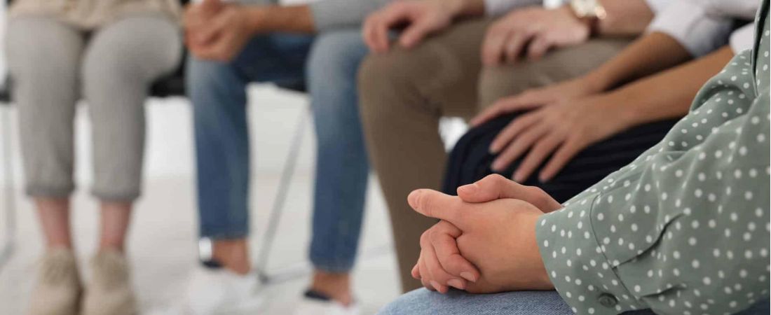 A group of people sit around in a circle discussing their struggles with addiction