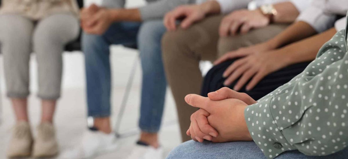 A group of people sit around in a circle discussing their struggles with addiction