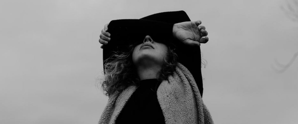 young girl with curly hair wraps her arms around her face as she looks up