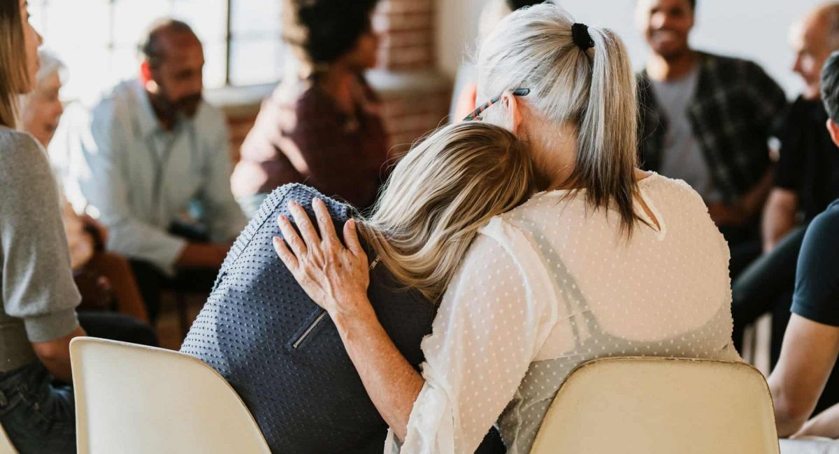 two women hug at a support group