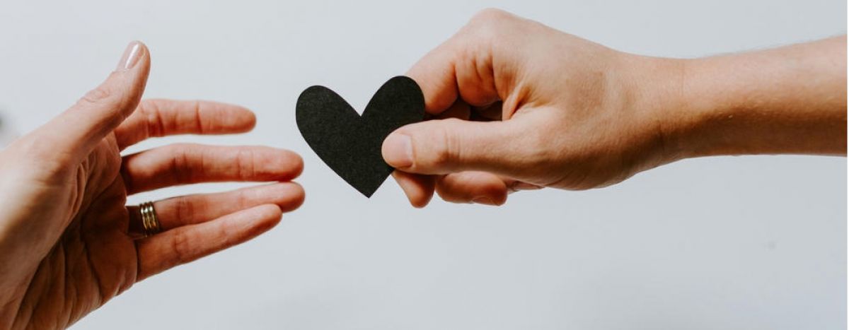 Two people passing a piece of paper shaped like a heart