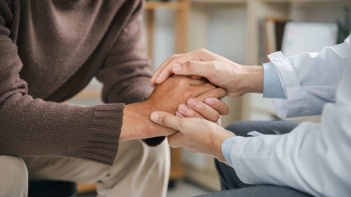 Therapist supporting patient with hand holding during Nashville addiction treatment.