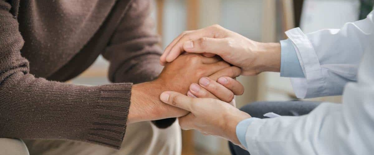 Therapist supporting patient with hand holding during Nashville addiction treatment.