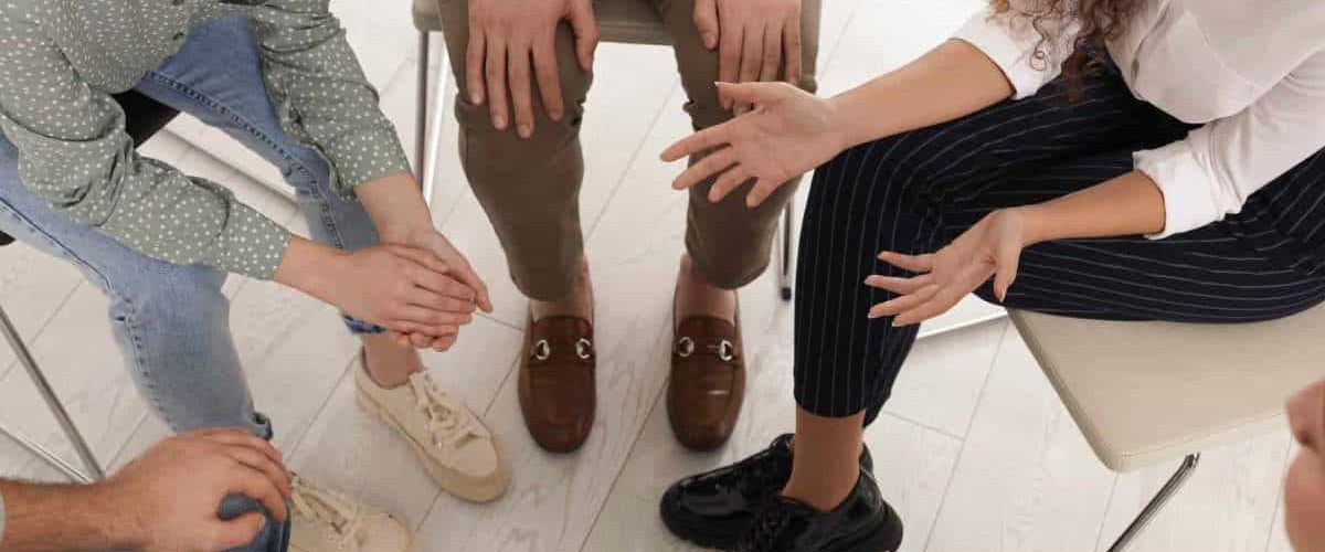 A supportive group therapy session where individuals openly share their thoughts, sparking the consideration: Do I need rehab?