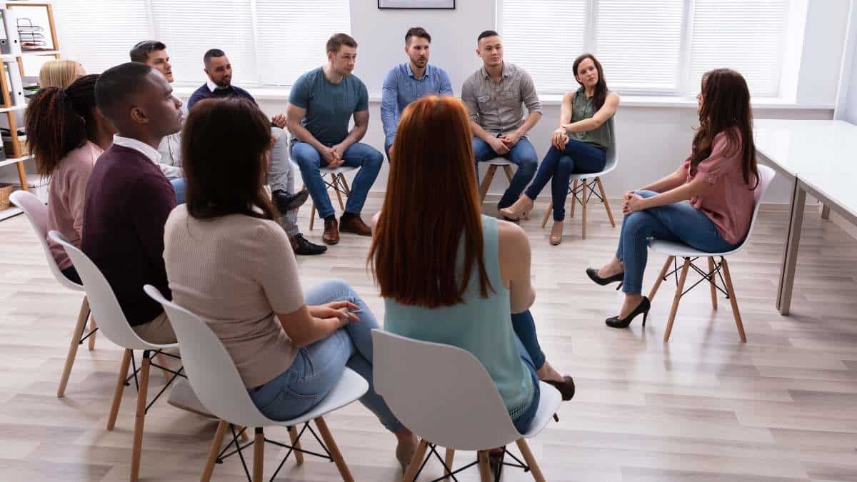 A supportive group therapy session where individuals openly share their thoughts, sparking the consideration: Do I need rehab?