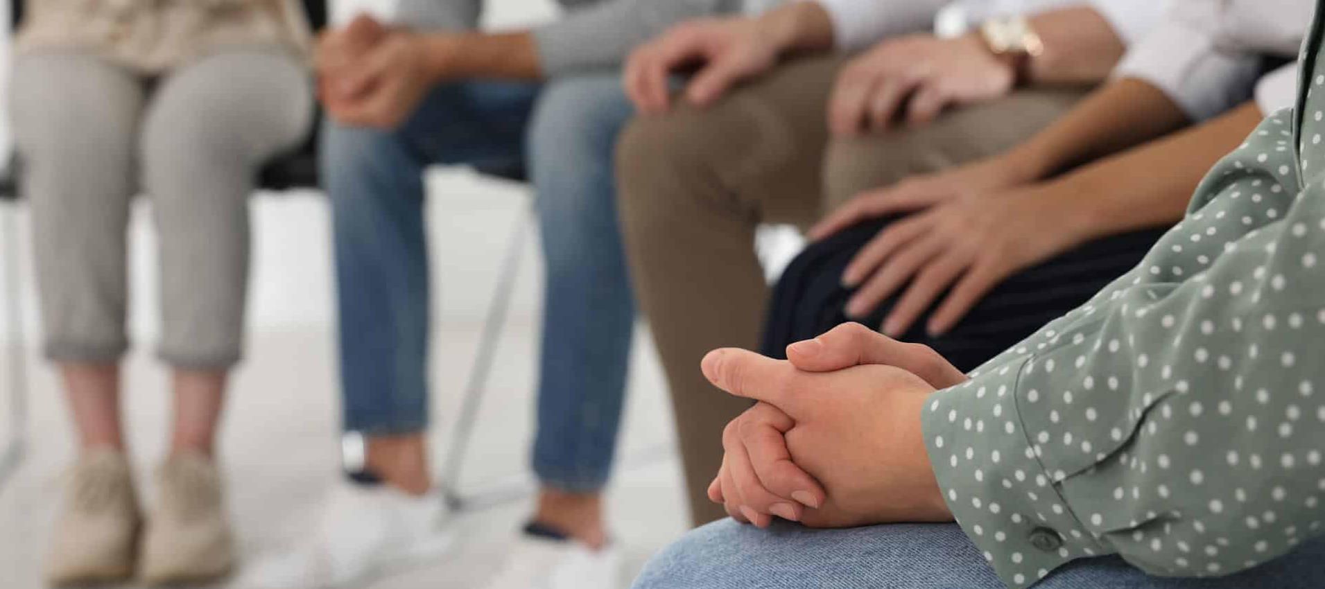 A group of people sit around in a circle discussing their struggles with addiction