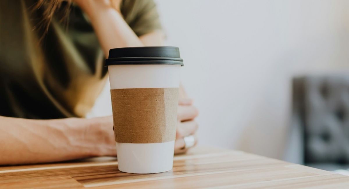 girl sits at a desk with a cup of coffee to go representing substance abuse treatment
