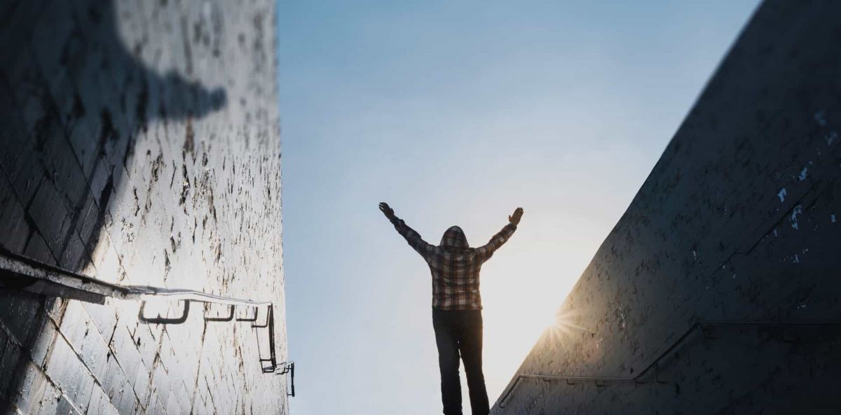 Man stands on top of a platform with his arms in the arm proud of his accomplishment