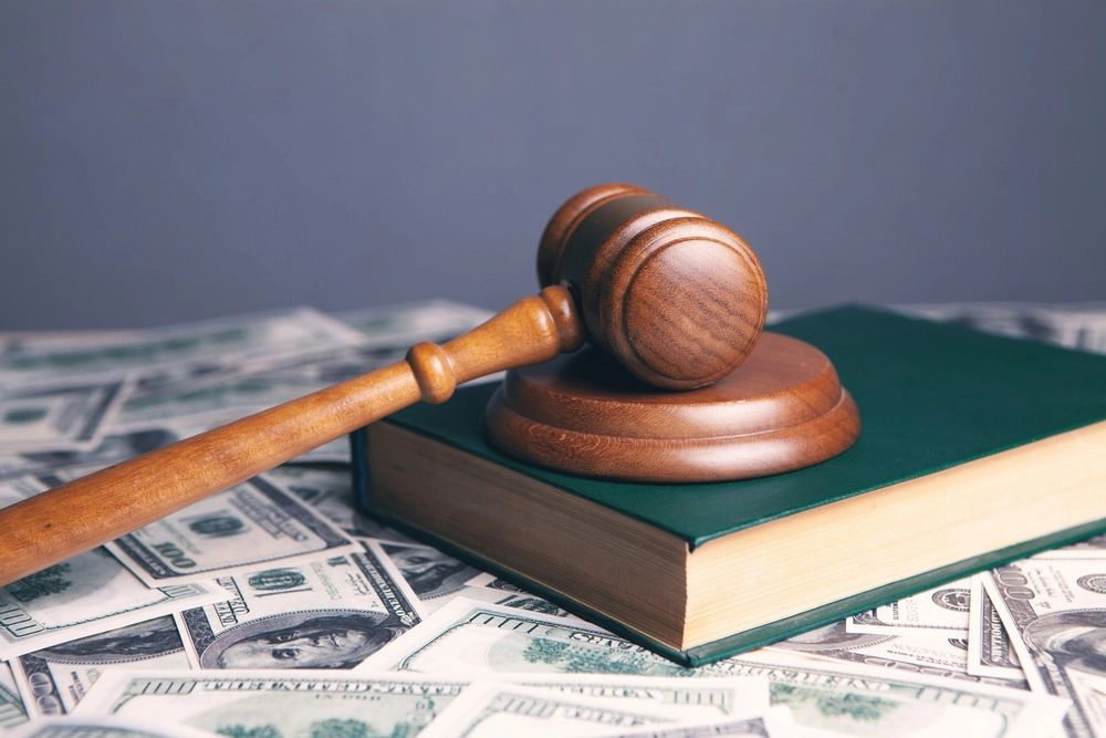 Gavel and book on top of money on a table